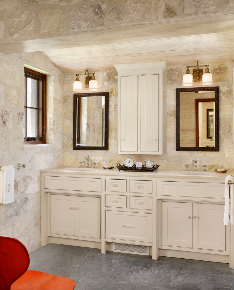 Exemple d'une salle de bain nature avec un lavabo encastré, un placard à porte affleurante, des portes de placard beiges, un carrelage de pierre et un mur en pierre.