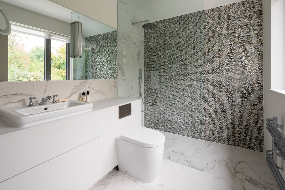 Photo of a large contemporary bathroom in London with flat-panel cabinets, beige cabinets, a corner shower, a one-piece toilet, mosaic tiles, marble flooring, a vessel sink, white floors, an open shower and white worktops.