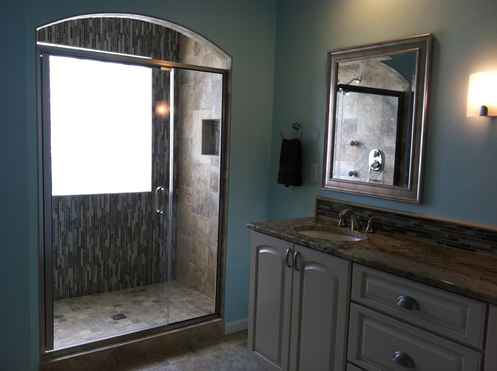 Example of a mid-sized classic master beige tile and brown tile alcove shower design in Cincinnati with raised-panel cabinets, beige cabinets, blue walls and an undermount sink