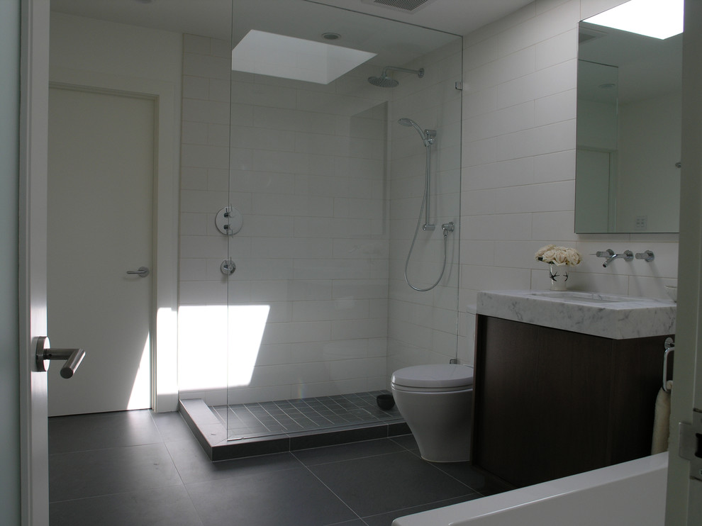 Réalisation d'une petite salle de bain minimaliste en bois brun pour enfant avec un placard avec porte à panneau encastré, un plan de toilette en marbre, une baignoire d'angle, une douche d'angle, WC à poser, un carrelage blanc, des carreaux de céramique et un mur blanc.