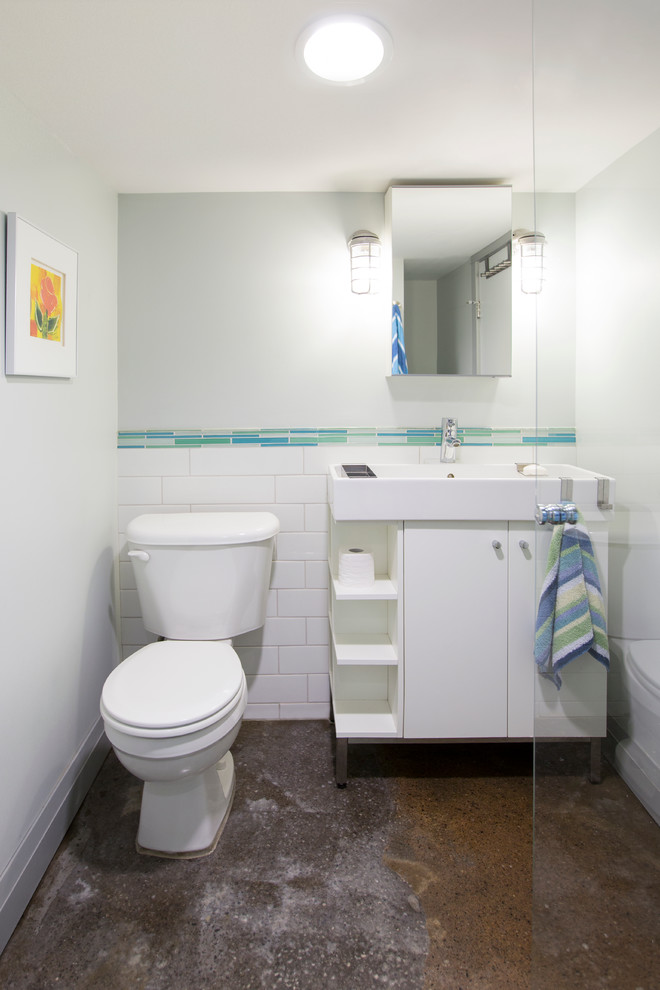 Foto di una piccola stanza da bagno design con lavabo a consolle, ante lisce, ante bianche, doccia alcova, WC a due pezzi, piastrelle bianche, piastrelle in ceramica, pareti grigie e pavimento in cemento