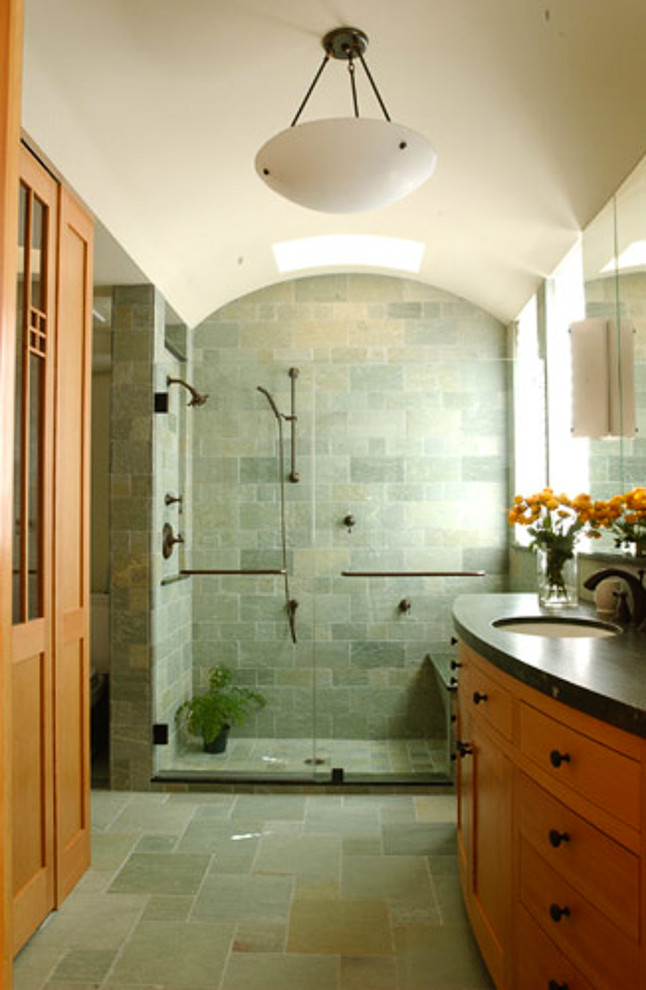 Diseño de cuarto de baño de estilo americano con puertas de armario de madera clara, ducha empotrada, baldosas y/o azulejos verdes, baldosas y/o azulejos de piedra, paredes blancas, suelo de piedra caliza y encimera de piedra caliza