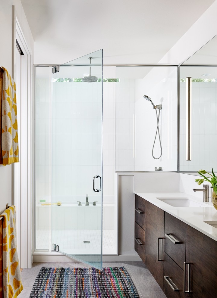 Bild på ett funkis en-suite badrum, med släta luckor, skåp i mörkt trä, en dusch/badkar-kombination och vita väggar