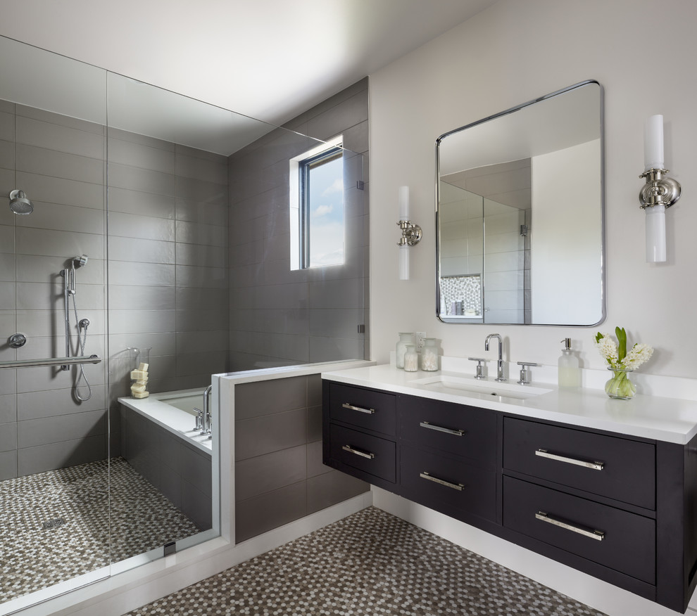 Inspiration for a large eclectic ensuite bathroom in Denver with flat-panel cabinets, black cabinets, a built-in bath, a shower/bath combination, grey tiles, metro tiles, white walls, mosaic tile flooring, a built-in sink, solid surface worktops, a hinged door, white worktops and multi-coloured floors.