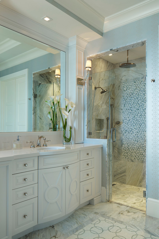 Пример оригинального дизайна: большая ванная комната в морском стиле с врезной раковиной, фасадами с выступающей филенкой, белыми фасадами, душем без бортиков, синей плиткой, серой плиткой, мраморной плиткой, синими стенами, мраморным полом, душевой кабиной, столешницей из искусственного кварца, серым полом, душем с распашными дверями и белой столешницей