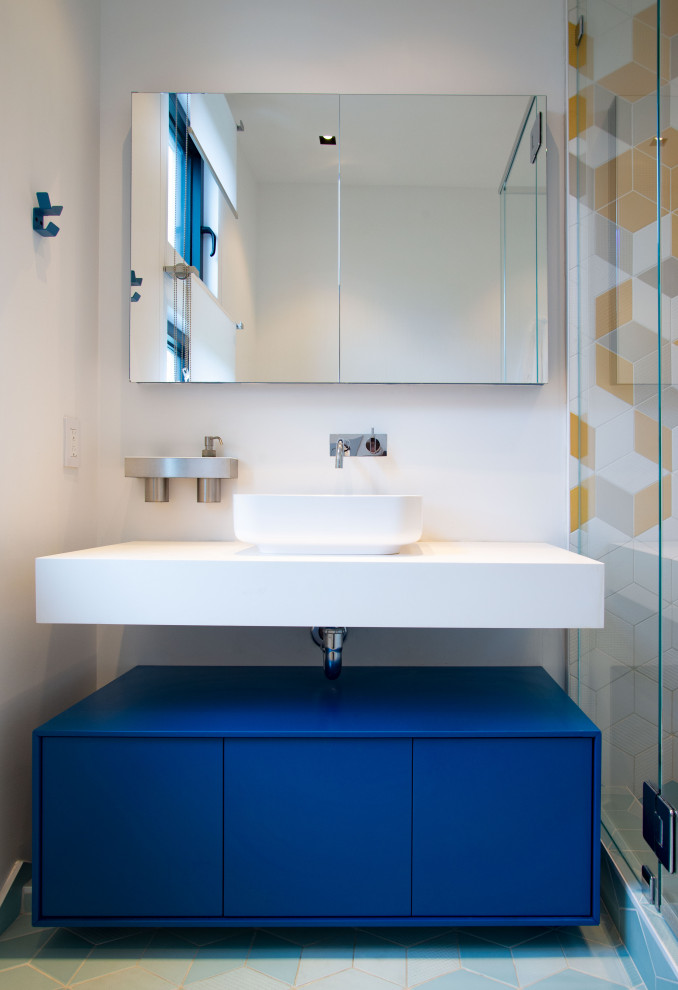 Foto di una piccola stanza da bagno per bambini minimal con ante lisce, ante blu, doccia alcova, piastrelle gialle, piastrelle in ceramica, pavimento con piastrelle in ceramica, lavabo integrato, top in superficie solida, pavimento blu, porta doccia a battente, top bianco, un lavabo e mobile bagno sospeso