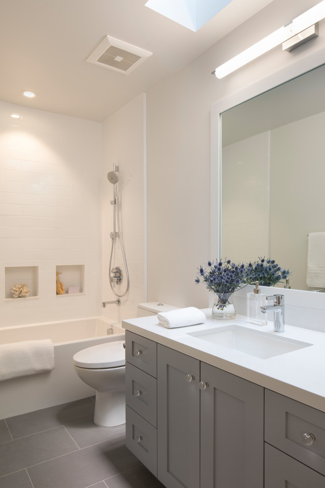 Inspiration för mellanstora klassiska badrum, med skåp i shakerstil, blå skåp, ett badkar i en alkov, en dusch/badkar-kombination, en toalettstol med hel cisternkåpa, vit kakel, keramikplattor, vita väggar, ett undermonterad handfat, bänkskiva i akrylsten, dusch med duschdraperi, klinkergolv i porslin och grått golv
