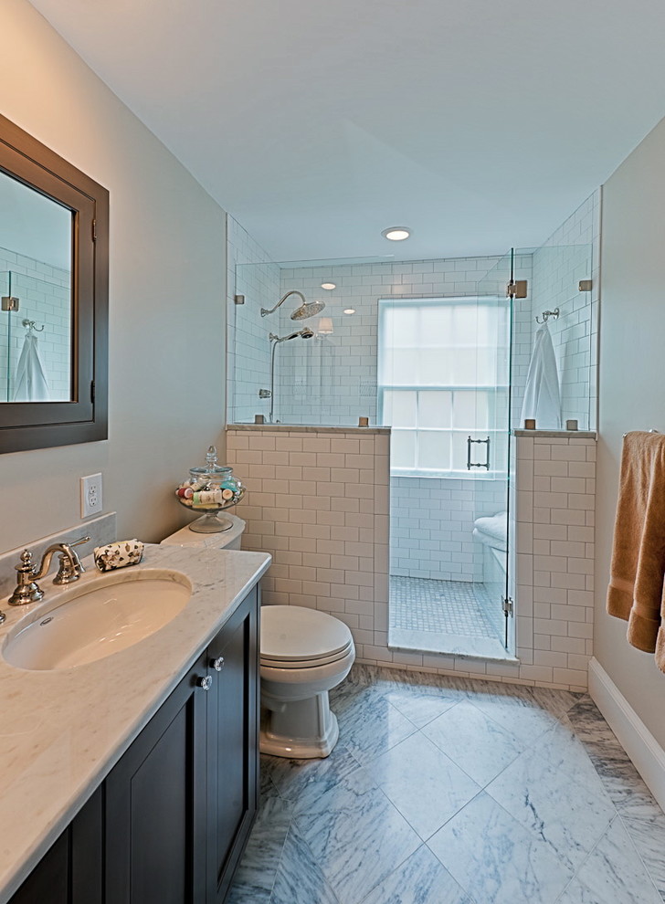 Klassisk inredning av ett litet en-suite badrum, med ett undermonterad handfat, grå skåp, marmorbänkskiva, en dusch i en alkov, en toalettstol med separat cisternkåpa, vit kakel, keramikplattor, marmorgolv, grå väggar och skåp i shakerstil