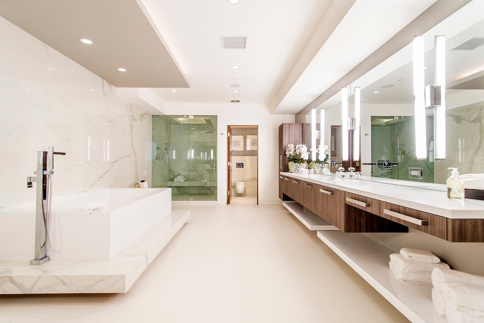 Inspiration for an expansive contemporary ensuite bathroom in Los Angeles with a hinged door, flat-panel cabinets, medium wood cabinets, a freestanding bath, an alcove shower, marble tiles, white walls, concrete flooring, solid surface worktops and beige floors.