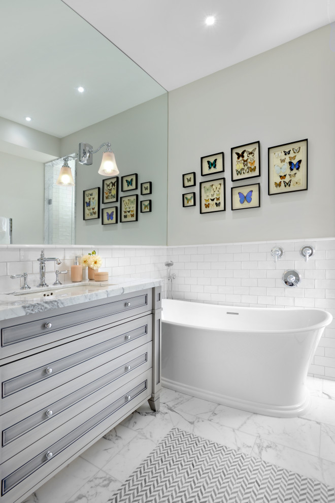 Свежая идея для дизайна: детская ванная комната среднего размера в классическом стиле с серыми фасадами, отдельно стоящей ванной, белой плиткой, плиткой кабанчик, серыми стенами, мраморным полом, врезной раковиной, мраморной столешницей, белым полом, белой столешницей и фасадами с утопленной филенкой - отличное фото интерьера