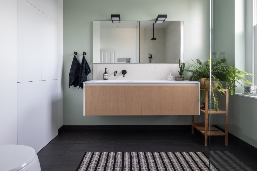На фото: ванная комната в современном стиле с плоскими фасадами, фасадами цвета дерева среднего тона, серыми стенами, душевой кабиной, монолитной раковиной, черным полом и белой столешницей с