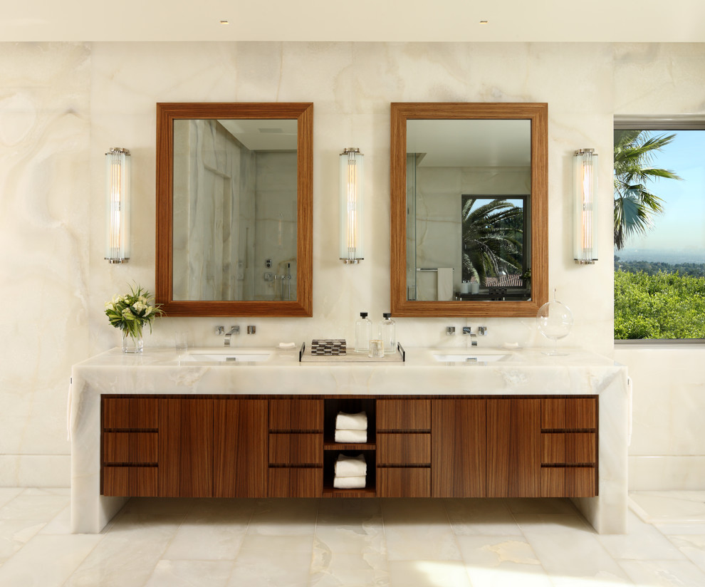 Immagine di una stanza da bagno contemporanea con lavabo sottopiano, ante lisce, ante in legno bruno, top in onice, pareti beige e piastrelle beige