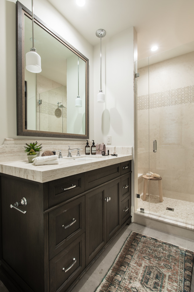 Photo of a traditional shower room bathroom in Orange County with recessed-panel cabinets, brown cabinets, an alcove shower, beige tiles, white walls, a submerged sink, grey floors and a hinged door.