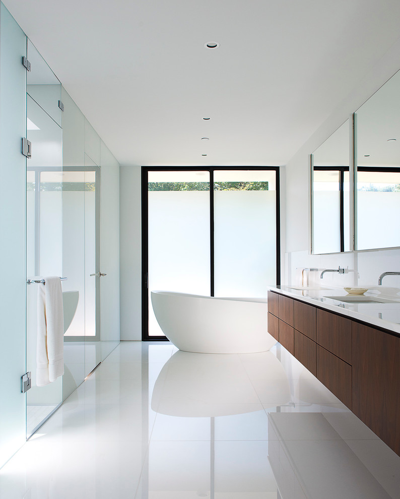 Пример оригинального дизайна: главная ванная комната в стиле модернизм с врезной раковиной, плоскими фасадами, темными деревянными фасадами, отдельно стоящей ванной, душем без бортиков, белыми стенами и белым полом