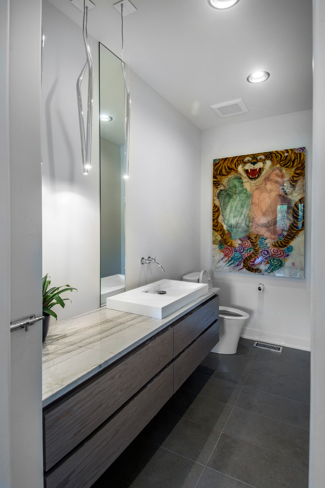 Mid-sized trendy 3/4 gray tile and porcelain tile porcelain tile and gray floor bathroom photo in Other with a vessel sink, flat-panel cabinets, white walls, gray cabinets, a one-piece toilet and quartzite countertops