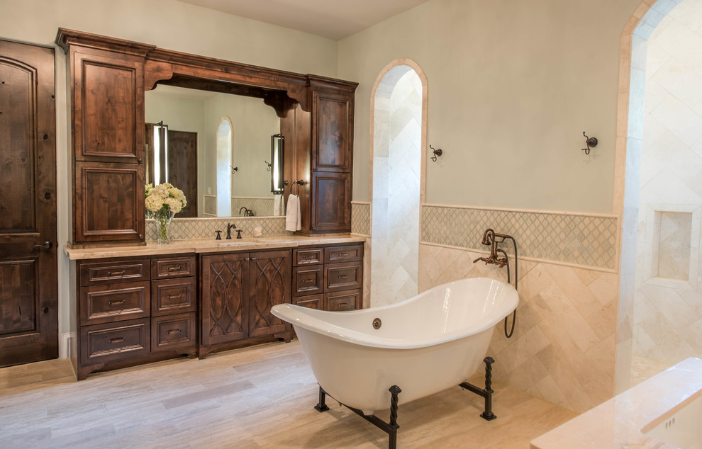Example of a large tuscan master beige tile and ceramic tile ceramic tile and beige floor freestanding bathtub design in Houston with raised-panel cabinets, dark wood cabinets, green walls, an undermount sink and marble countertops