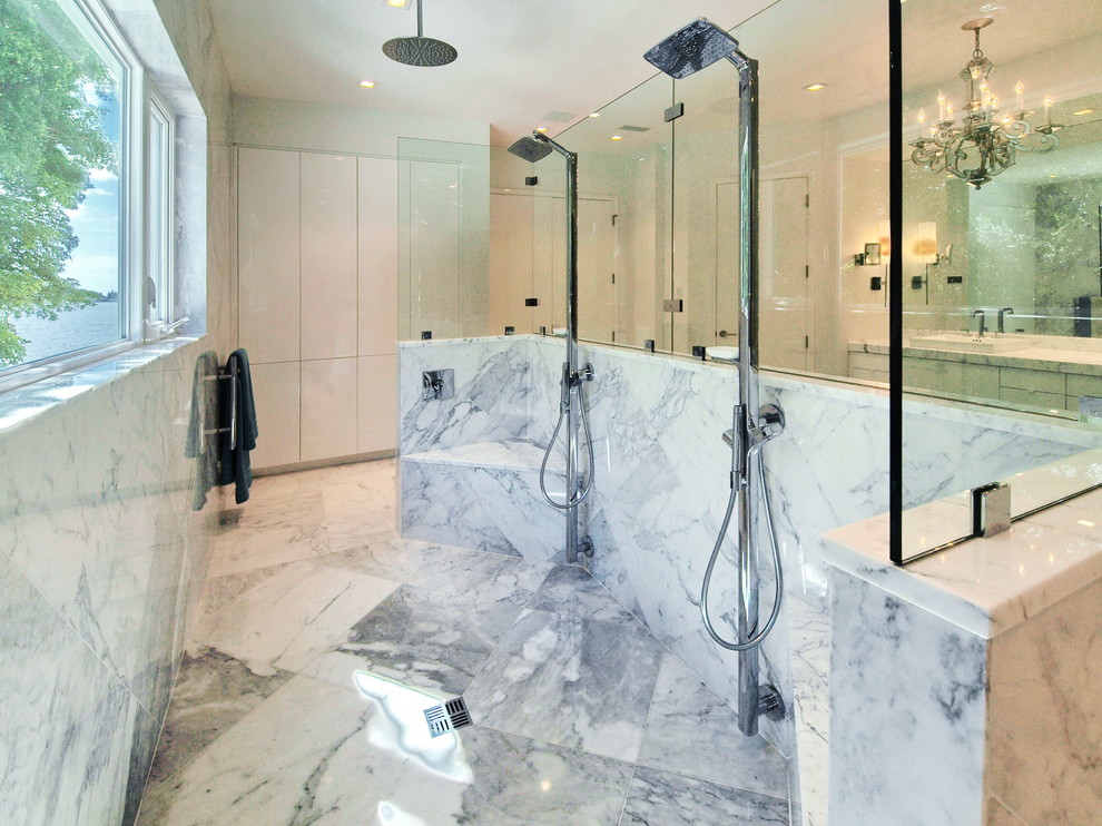 На фото: огромная главная ванная комната в стиле модернизм с плоскими фасадами, белыми фасадами, отдельно стоящей ванной, двойным душем, белой плиткой, каменной плиткой, белыми стенами, мраморным полом, настольной раковиной и мраморной столешницей