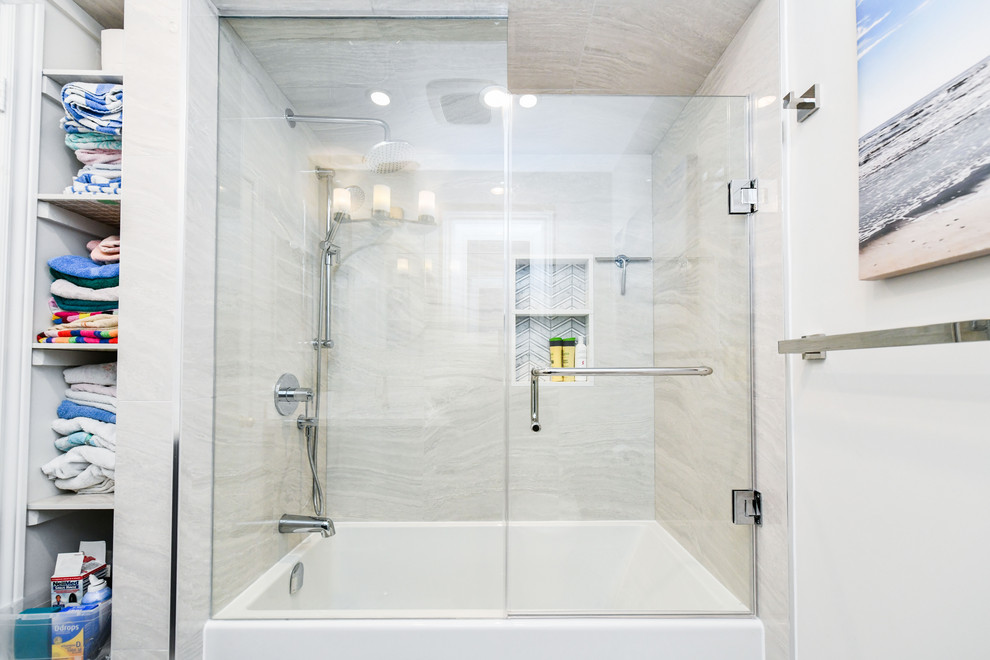 This is an example of a small traditional ensuite bathroom in Toronto with freestanding cabinets, blue cabinets, a built-in bath, a shower/bath combination, a one-piece toilet, multi-coloured tiles, porcelain tiles, white walls, mosaic tile flooring, a built-in sink, engineered stone worktops, multi-coloured floors, a hinged door and white worktops.
