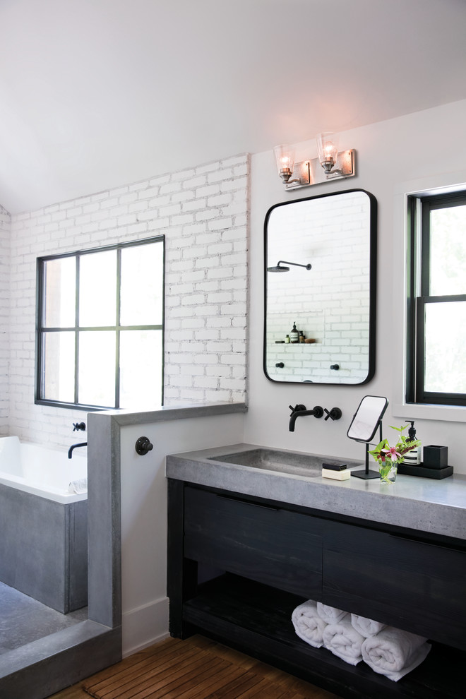 Diseño de cuarto de baño urbano sin sin inodoro con armarios con paneles lisos, puertas de armario negras, bañera esquinera, baldosas y/o azulejos blancos, paredes blancas, suelo de madera en tonos medios, aseo y ducha, lavabo integrado, encimera de cemento, suelo marrón y ducha abierta