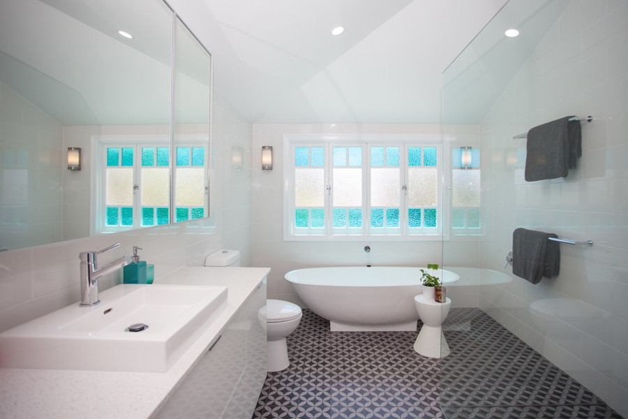 Photo of a medium sized world-inspired ensuite bathroom in Brisbane with flat-panel cabinets, white cabinets, a freestanding bath, a corner shower, a one-piece toilet, white tiles, metro tiles, a vessel sink, engineered stone worktops, an open shower, white walls, ceramic flooring and grey floors.