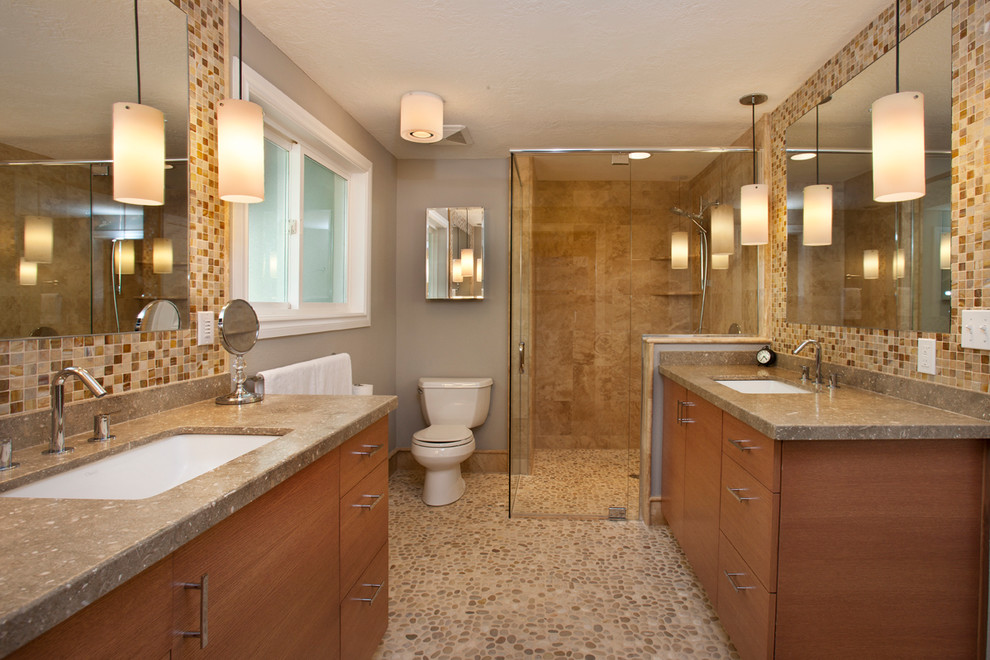 Corner shower - mid-sized transitional master multicolored tile and glass tile pebble tile floor corner shower idea in Boise with an undermount sink, flat-panel cabinets, medium tone wood cabinets, limestone countertops, a two-piece toilet and gray walls