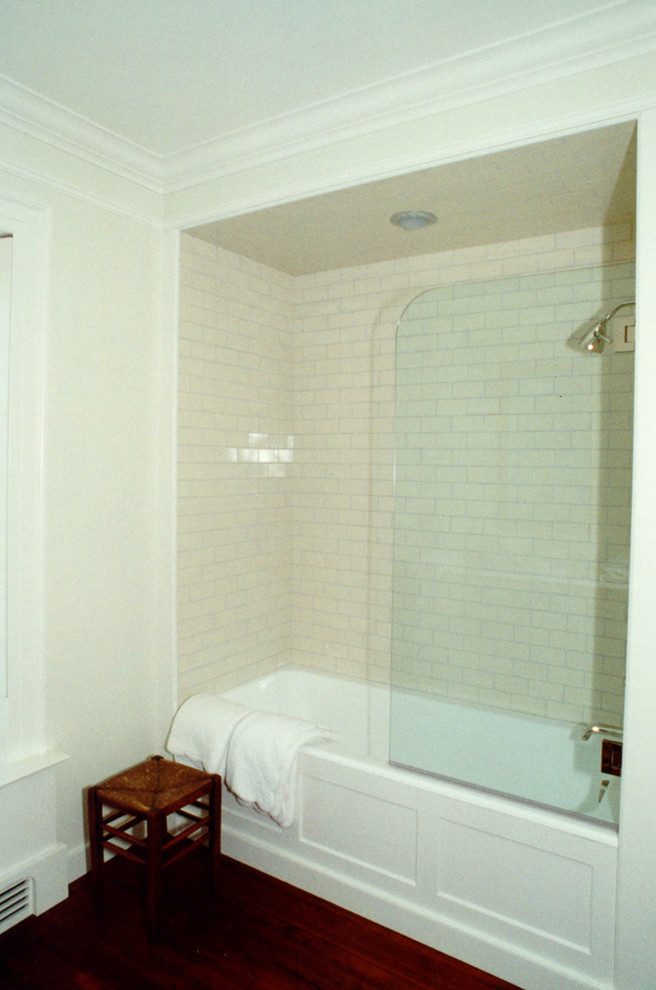 Exempel på ett mellanstort klassiskt badrum med dusch, med ett undermonterad handfat, släta luckor, vita skåp, marmorbänkskiva, ett badkar i en alkov, en dusch/badkar-kombination, en toalettstol med separat cisternkåpa, vit kakel, tunnelbanekakel, vita väggar och mellanmörkt trägolv