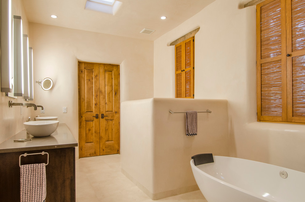 Exemple d'une salle de bain principale sud-ouest américain en bois foncé de taille moyenne avec une vasque, une baignoire indépendante et un mur beige.