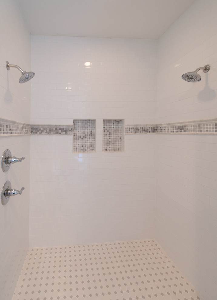 Klassisk inredning av ett badrum, med skåp i shakerstil, skåp i mörkt trä, ett fristående badkar, en dusch i en alkov, en toalettstol med separat cisternkåpa, vit kakel, keramikplattor, grå väggar, marmorgolv, ett undermonterad handfat och marmorbänkskiva