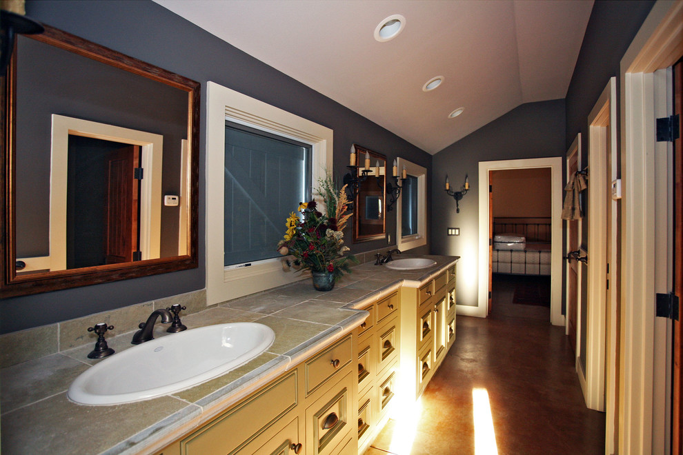 Example of a large mountain style master gray tile and stone tile concrete floor bathroom design in San Francisco with recessed-panel cabinets, light wood cabinets, green walls, a drop-in sink and tile countertops