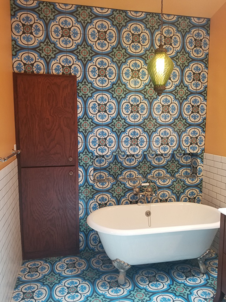 На фото: большая главная ванная комната в стиле неоклассика (современная классика) с коричневыми фасадами, ванной на ножках, угловым душем, синей плиткой, цементной плиткой, оранжевыми стенами, синим полом, душем с распашными дверями, белой столешницей, тумбой под одну раковину, встроенной тумбой, полом из керамической плитки, монолитной раковиной и столешницей из искусственного камня