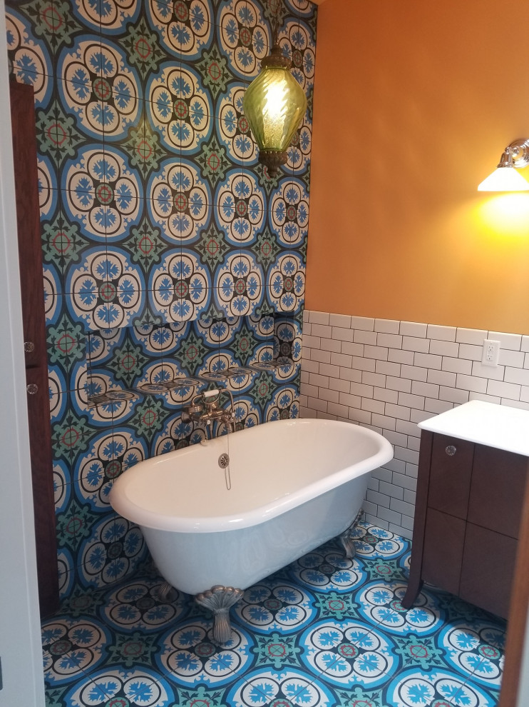 На фото: большая главная ванная комната в стиле неоклассика (современная классика) с коричневыми фасадами, ванной на ножках, угловым душем, синей плиткой, цементной плиткой, оранжевыми стенами, синим полом, душем с распашными дверями, белой столешницей, тумбой под одну раковину, встроенной тумбой, полом из цементной плитки, монолитной раковиной и столешницей из искусственного камня с