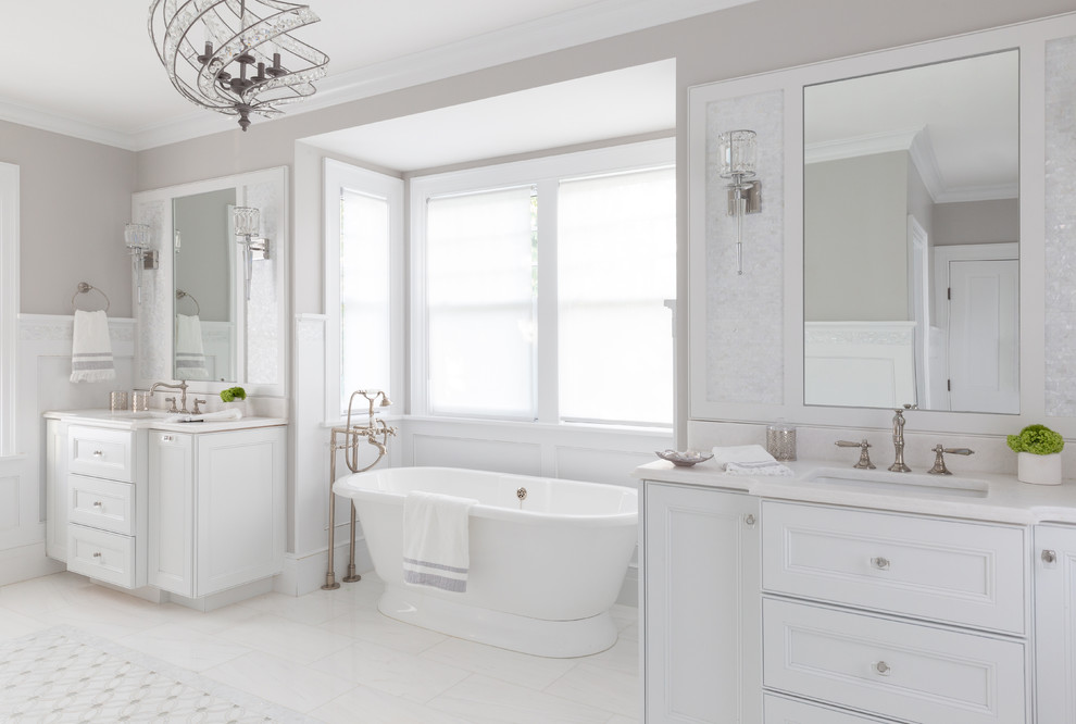 На фото: большая главная ванная комната в морском стиле с фасадами островного типа, белыми фасадами, отдельно стоящей ванной, душем в нише, унитазом-моноблоком, белой плиткой, мраморной плиткой, серыми стенами, мраморным полом, накладной раковиной, мраморной столешницей, белым полом, душем с распашными дверями и белой столешницей с