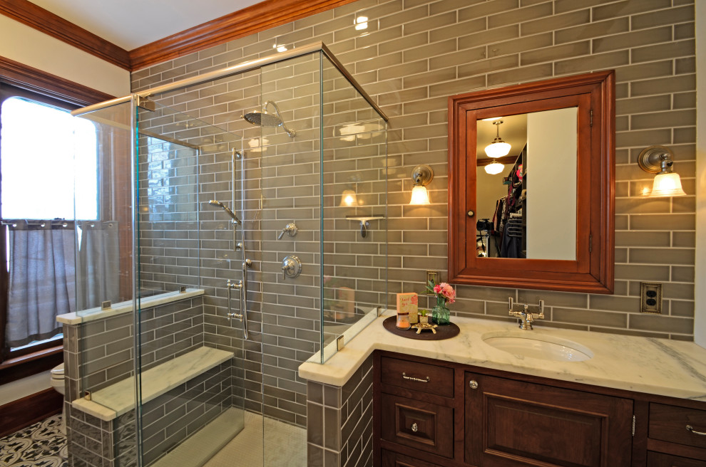 Design ideas for a large victorian ensuite bathroom in Milwaukee with beaded cabinets, medium wood cabinets, a built-in shower, a two-piece toilet, grey tiles, porcelain tiles, porcelain flooring, a built-in sink, granite worktops, a hinged door, white worktops, a shower bench, a single sink and a built in vanity unit.