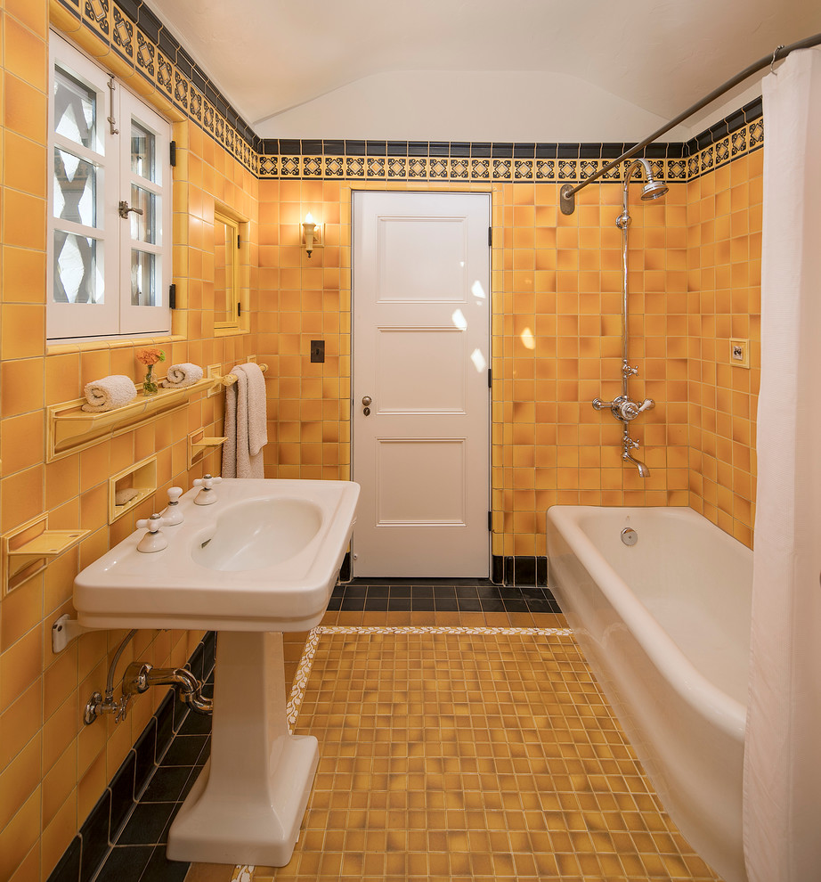 Foto på ett litet medelhavsstil en-suite badrum, med ett hörnbadkar, en dusch/badkar-kombination, gul kakel, keramikplattor, gula väggar, klinkergolv i keramik, ett piedestal handfat och dusch med duschdraperi