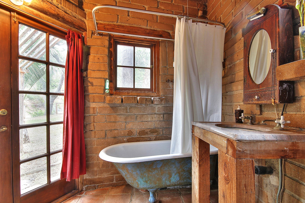 На фото: ванная комната в стиле рустика с врезной раковиной, ванной на ножках и окном