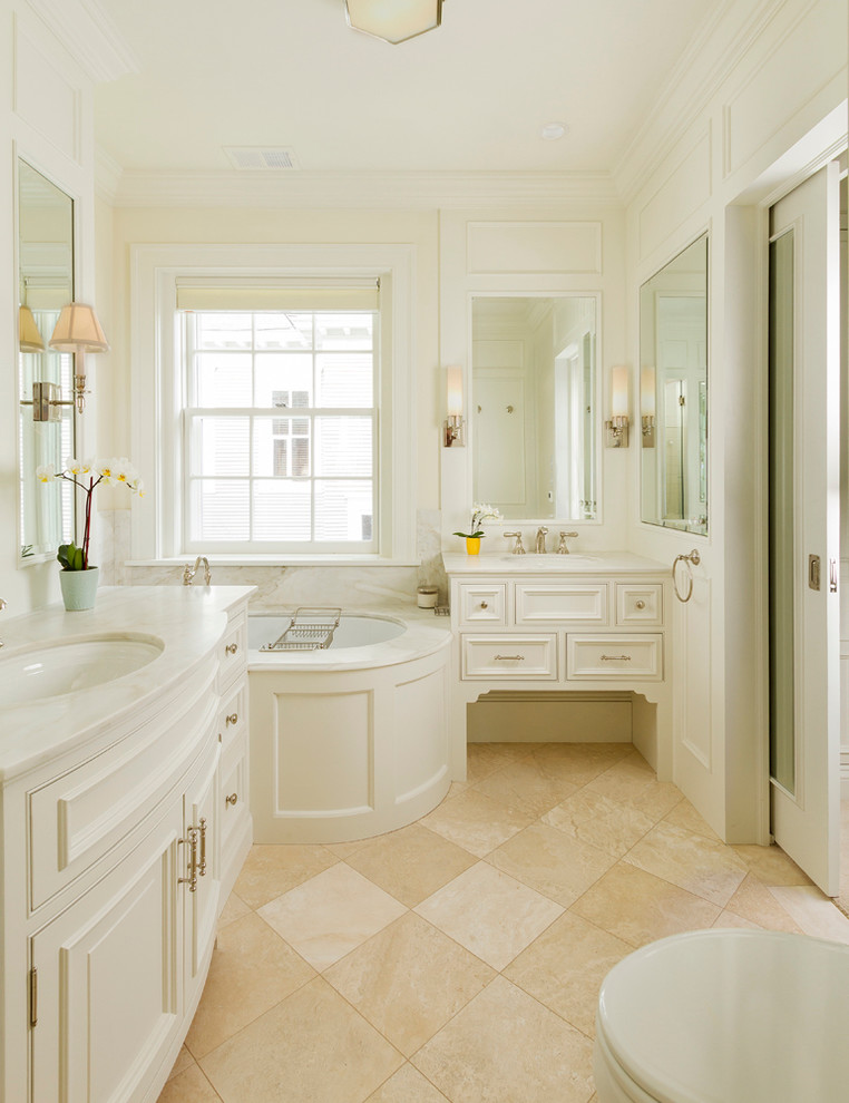 Стильный дизайн: большая главная ванная комната в классическом стиле с фасадами с декоративным кантом, белыми фасадами, полновстраиваемой ванной, душевой комнатой, унитазом-моноблоком, бежевой плиткой, каменной плиткой, бежевыми стенами, мраморным полом, врезной раковиной и мраморной столешницей - последний тренд