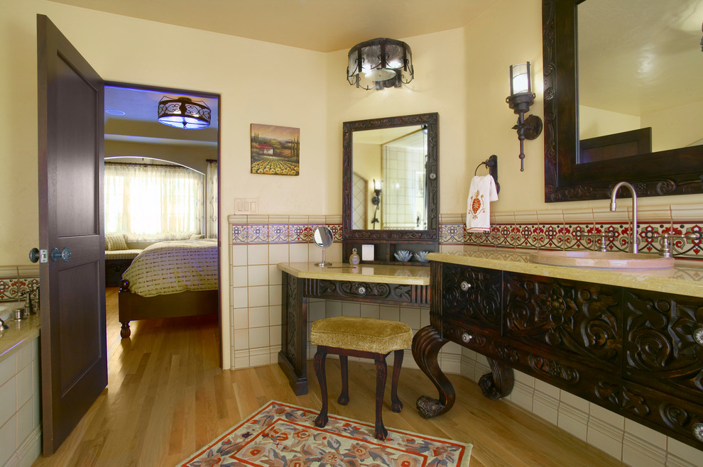 Mediterranean bathroom in San Diego with a built-in sink, dark wood cabinets, granite worktops, a built-in bath, multi-coloured tiles, ceramic tiles, yellow walls and light hardwood flooring.