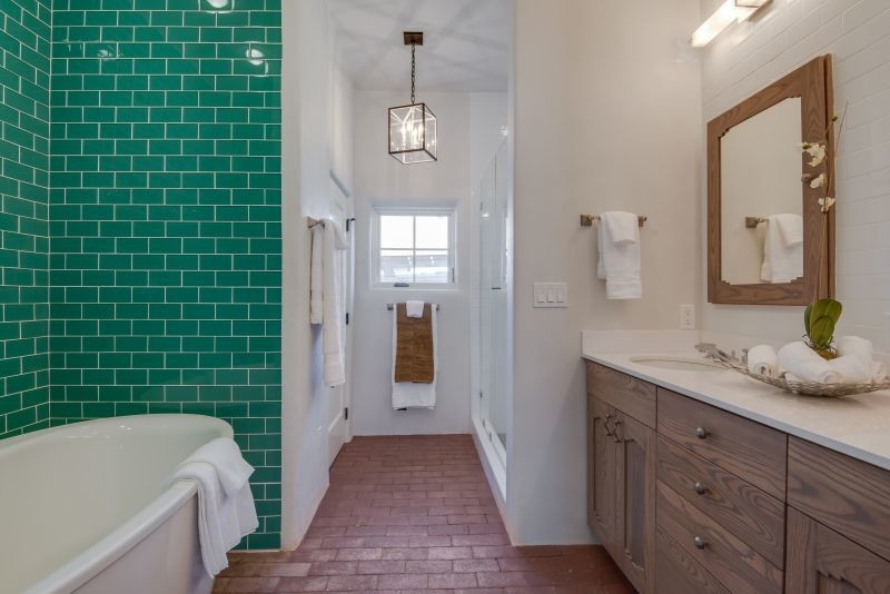 Aménagement d'une salle de bain principale sud-ouest américain en bois brun de taille moyenne avec un lavabo encastré, un placard avec porte à panneau encastré, un plan de toilette en surface solide, un combiné douche/baignoire, un carrelage blanc, un mur blanc et un sol en brique.