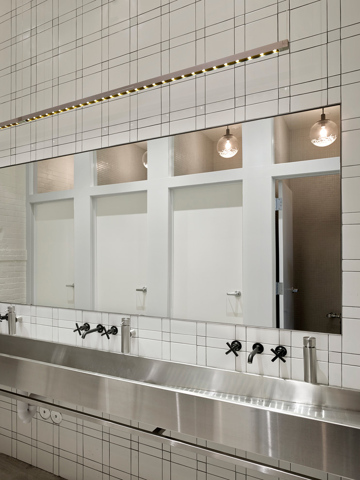 Imagen de cuarto de baño urbano grande con lavabo de seno grande, baldosas y/o azulejos blancos, baldosas y/o azulejos de cerámica, paredes blancas y suelo de cemento