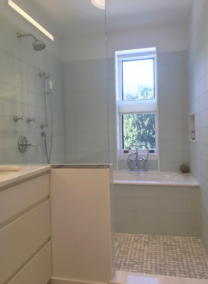 Inspiration for a medium sized modern grey and white ensuite bathroom in New York with flat-panel cabinets, white cabinets, a wall mounted toilet, white walls, marble flooring, grey floors, white worktops, a submerged bath, a built-in shower, white tiles, glass tiles, a submerged sink, marble worktops, an open shower, double sinks and a built in vanity unit.