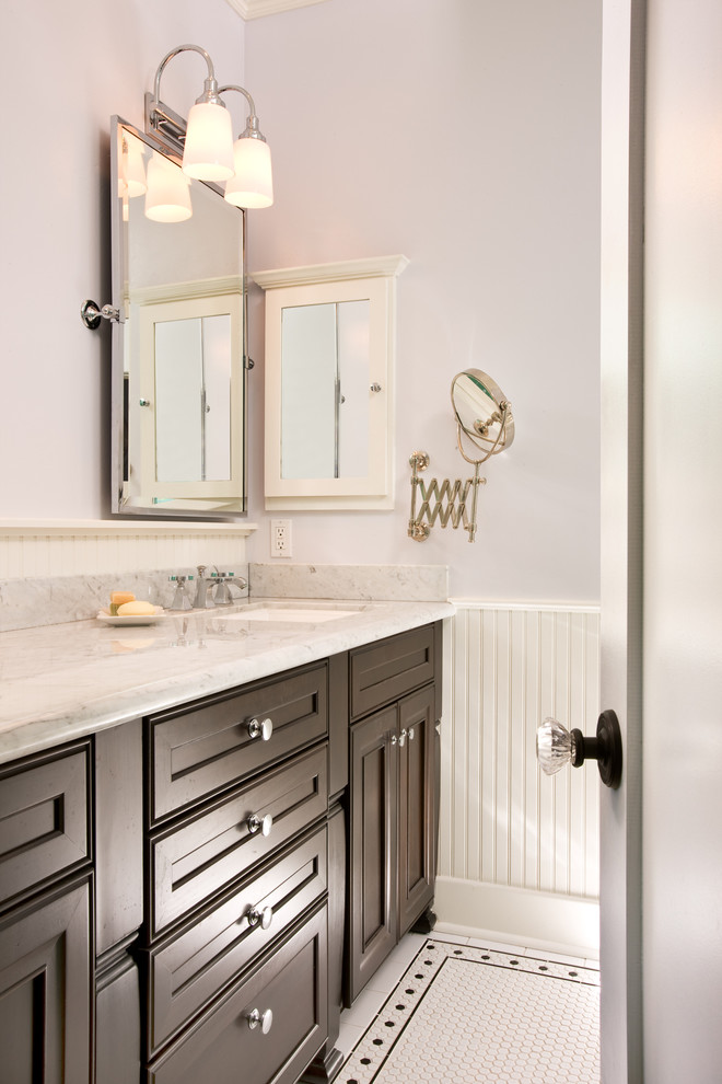 Immagine di una stanza da bagno tradizionale con lavabo sottopiano, ante con riquadro incassato, ante in legno bruno, top in marmo, pareti viola e pavimento con piastrelle a mosaico