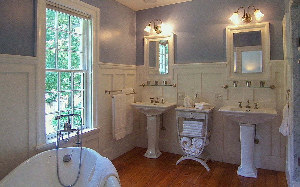 Esempio di una stanza da bagno padronale tradizionale di medie dimensioni con vasca con piedi a zampa di leone, pareti viola, pavimento in legno massello medio, lavabo a colonna e pavimento marrone