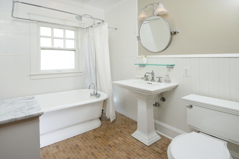 Imagen de cuarto de baño clásico con lavabo con pedestal, bañera exenta, combinación de ducha y bañera, baldosas y/o azulejos blancos, baldosas y/o azulejos de cemento y suelo de ladrillo