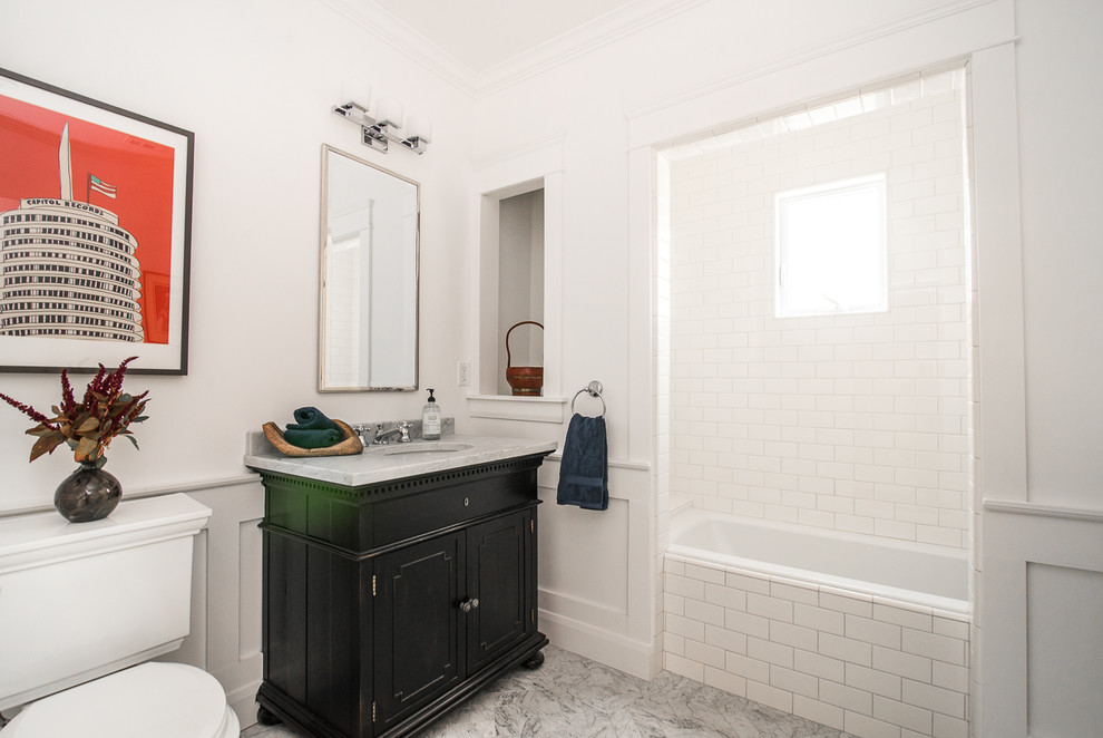 Klassisk inredning av ett mellanstort flerfärgad flerfärgat badrum med dusch, med möbel-liknande, svarta skåp, ett badkar i en alkov, en dusch/badkar-kombination, en toalettstol med separat cisternkåpa, vit kakel, tunnelbanekakel, vita väggar, marmorgolv, ett undermonterad handfat, bänkskiva i kvarts, flerfärgat golv och dusch med duschdraperi