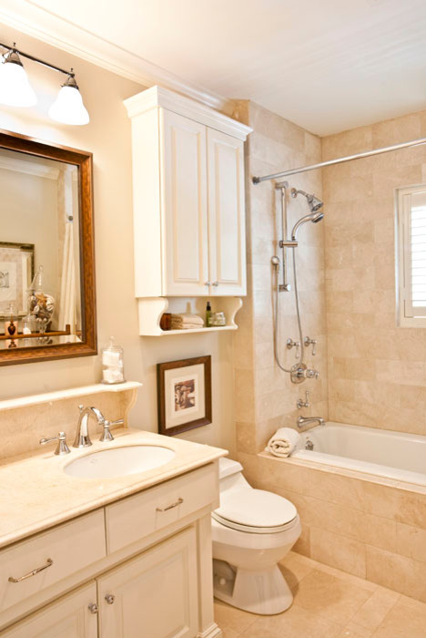 Photo of a medium sized classic ensuite bathroom in Houston with a submerged sink, raised-panel cabinets, white cabinets, a built-in bath, a shower/bath combination, a one-piece toilet, beige tiles, stone tiles, beige walls and travertine flooring.