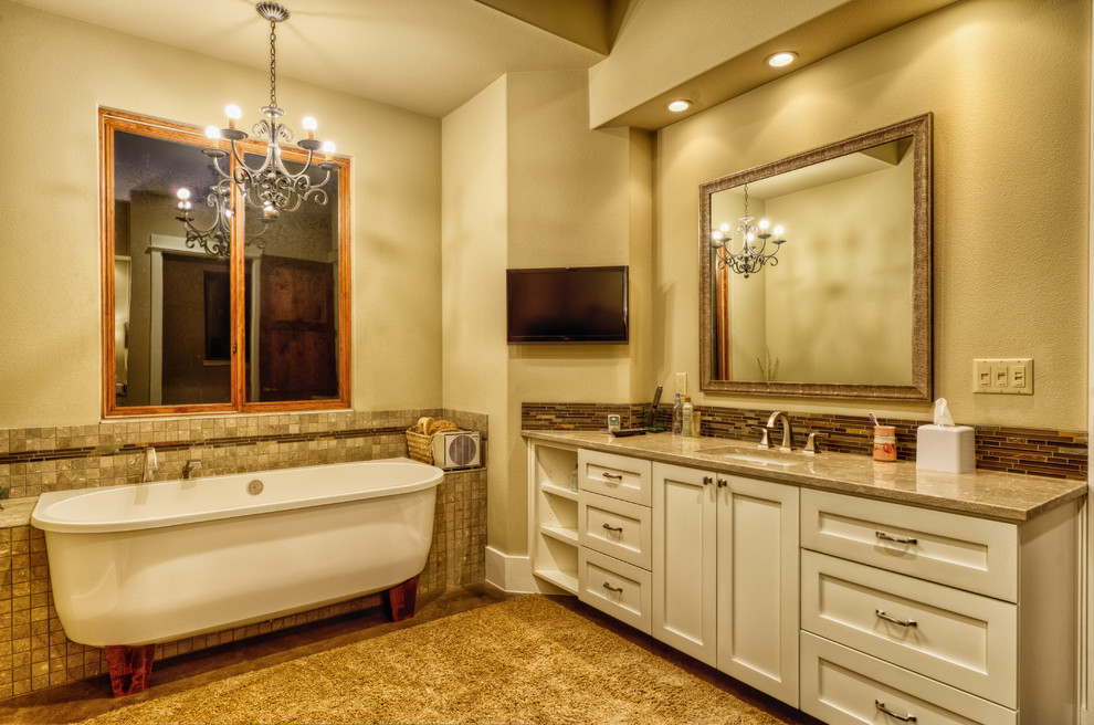Пример оригинального дизайна: большая главная ванная комната в средиземноморском стиле с угловым душем, разноцветной плиткой, стеклянной плиткой, белыми фасадами, бежевыми стенами, бетонным полом, врезной раковиной, ванной на ножках, столешницей из гранита, коричневым полом и бежевой столешницей