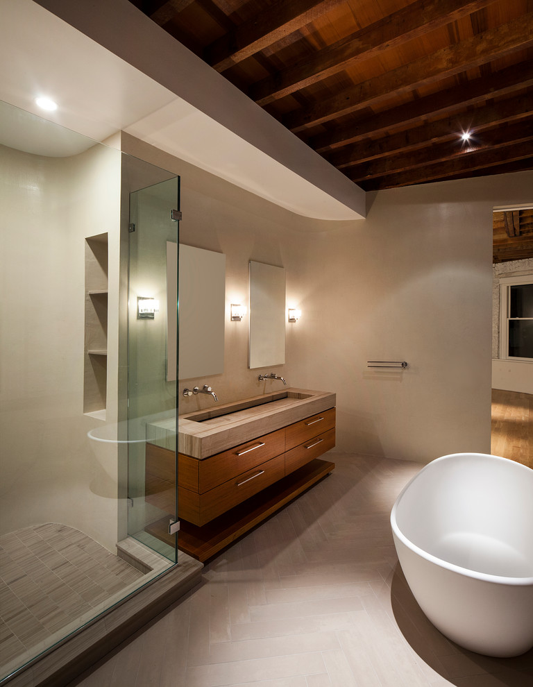 Modelo de cuarto de baño contemporáneo con lavabo de seno grande, armarios con paneles lisos, puertas de armario de madera oscura, bañera exenta y paredes beige