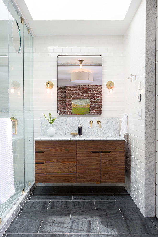 Modern ensuite bathroom in New York with flat-panel cabinets, dark wood cabinets, an alcove shower, white tiles, metro tiles, white walls, slate flooring, a submerged sink, marble worktops, grey floors and a hinged door.