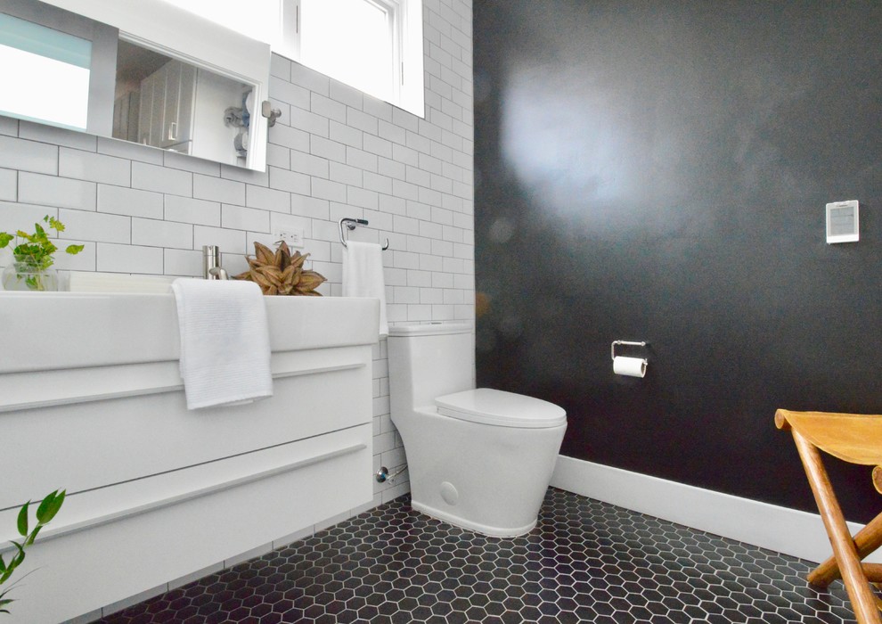 Design ideas for a medium sized modern ensuite bathroom in New York with flat-panel cabinets, white cabinets, a walk-in shower, a one-piece toilet, white tiles, metro tiles, black walls, ceramic flooring, an integrated sink, solid surface worktops, black floors, an open shower and white worktops.