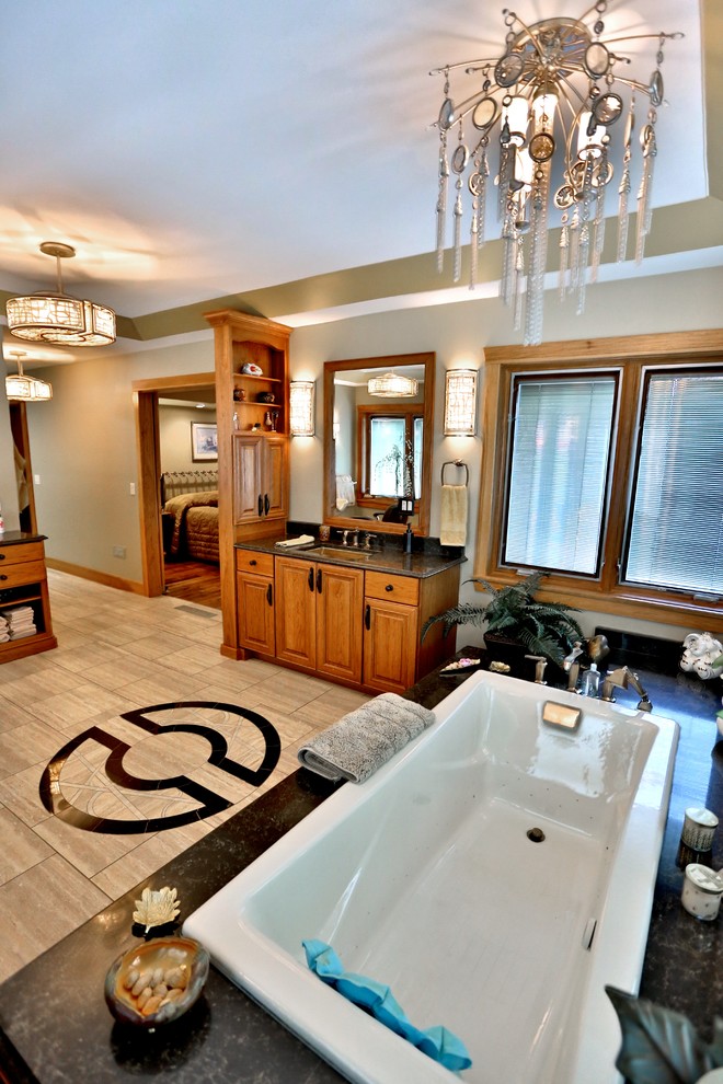Large traditional ensuite bathroom in Chicago with a submerged sink, raised-panel cabinets, medium wood cabinets, granite worktops, a built-in bath, beige tiles, stone tiles, beige walls and porcelain flooring.
